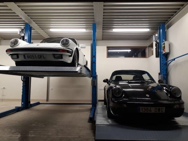 Dos coches apilados en un elevador de parking en un garaje particular